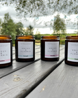 Four Angus & Florrie candles on a wooden surface with a natural background