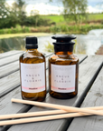 Two bottles of Angus & Florrie Meadow product on a wooden table with a scenic background.