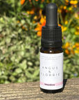 Bottle of Angus & Florrie essential oil with a dropper on a wooden surface with a natural background