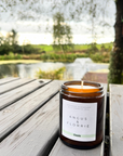 Candle in a jar labeled 'Angus & Florrie' on a wooden surface with a natural background
