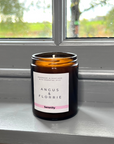 Candle in an amber jar with a label on a windowsill