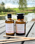 Two bottles of Angus & Florrie Serenity product on a wooden surface with a natural background.