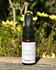 Bottle of Angus & Florrie essential oil with a garden background