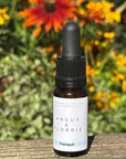 Bottle of Angus & Florrie Tranquil essential oil with flowers in the background