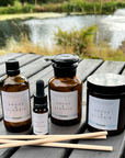 Collection of Angus & Florrie products including bottles, a candle, and sticks on a wooden surface with a natural background.