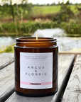 Candle in an amber jar with a label on a wooden surface, nature in the background