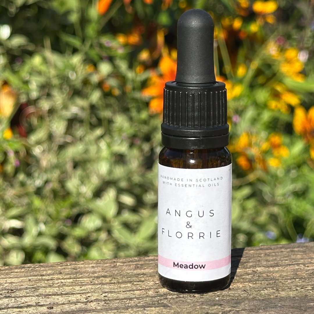 Bottle of Angus & Florrie essential oil with a dropper on a wooden surface with a natural background