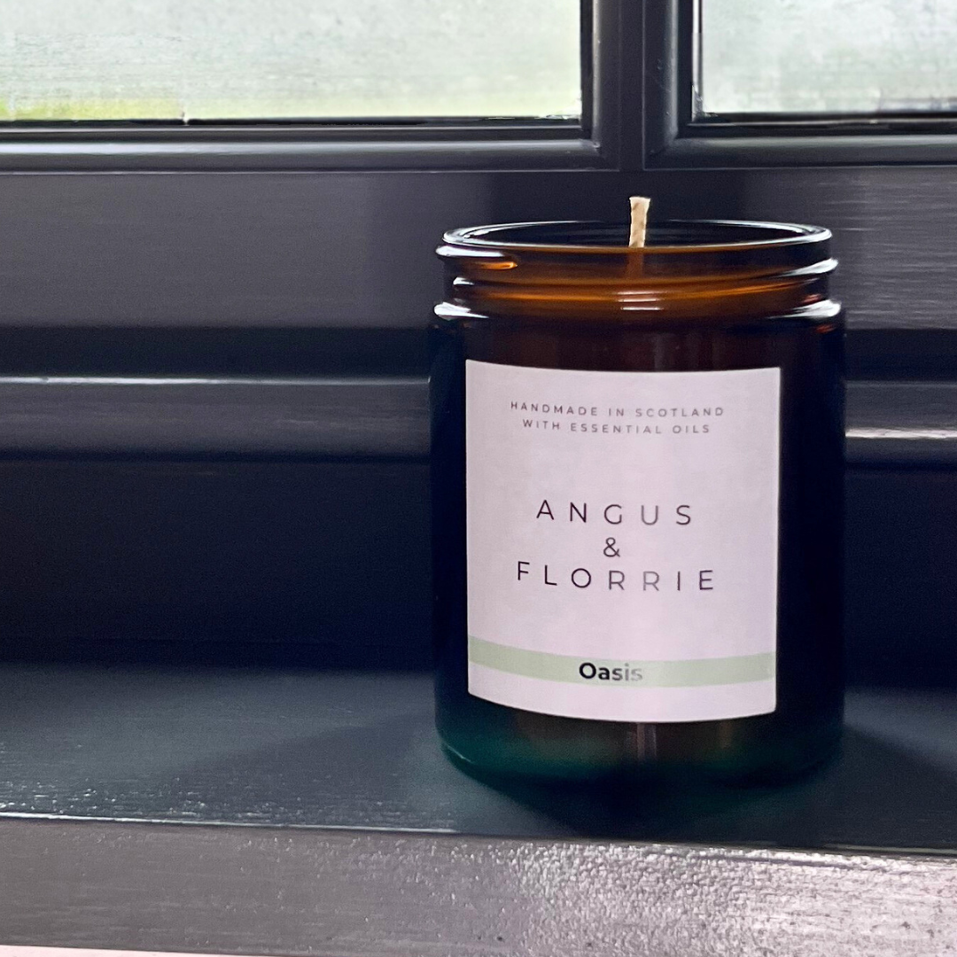Candle in a glass jar with a label on a reflective surface