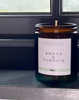 Candle in a glass jar with a label on a reflective surface