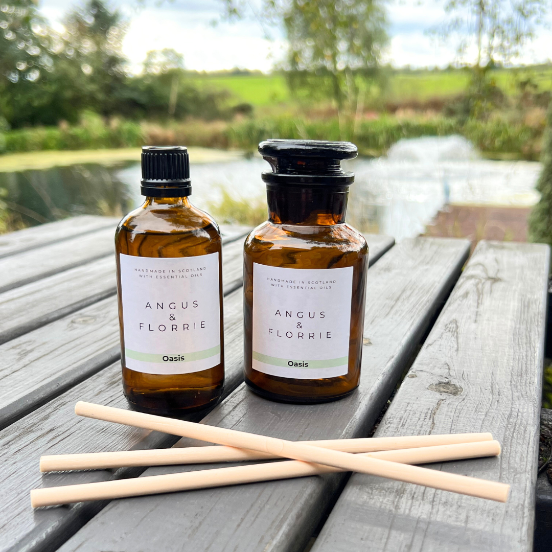 Two bottles of 'Angus & Florrie' product on a wooden table with a scenic background.