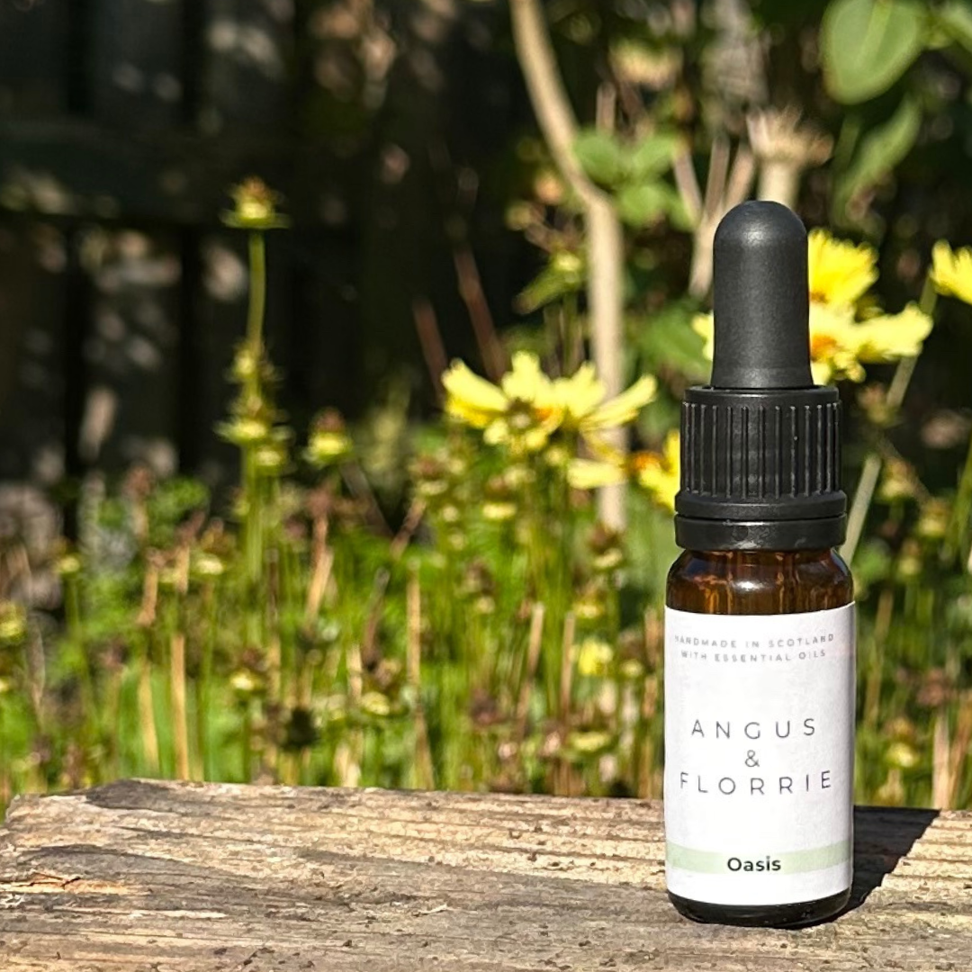 Bottle of Angus & Florrie Oasis essential oil with a dropper on a wooden surface with a natural background.