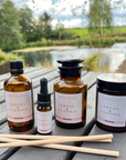 Four Angus & Florrie product bottles and a candle on a wooden surface with a natural background.