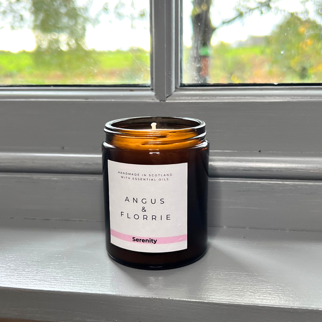 Candle in an amber jar with a label on a windowsill
