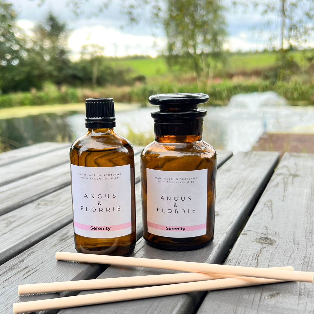 Two bottles of Angus & Florrie Serenity product on a wooden surface with a natural background.
