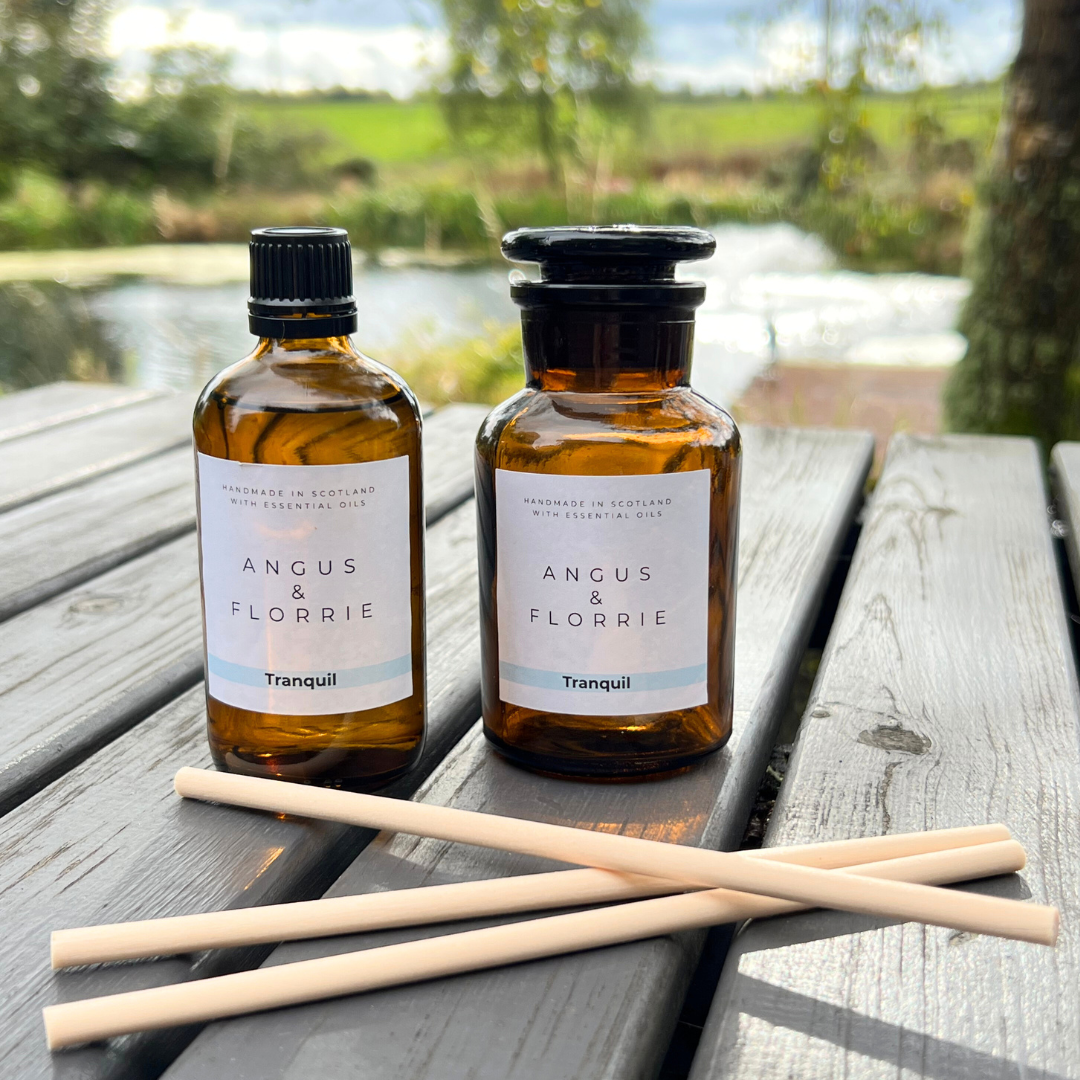 Two bottles of Angus & Florrie Tranquil product on a wooden table with a scenic background.