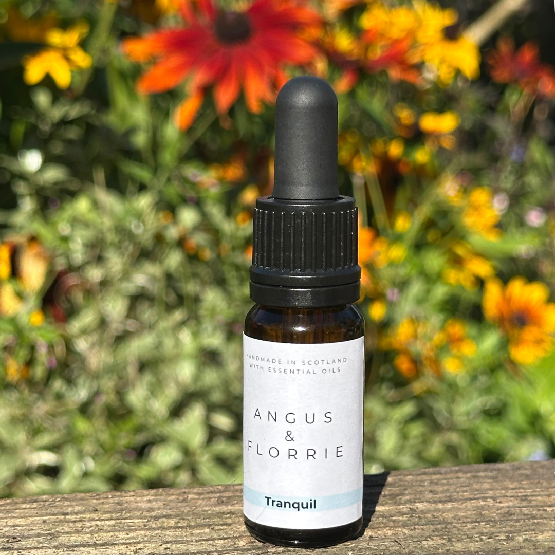 Bottle of Angus & Florrie Tranquil essential oil with flowers in the background