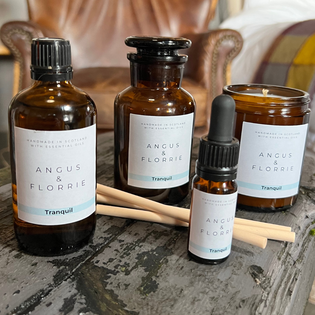 Angus & Florrie product bottles and candles on a stone surface with a blurred background