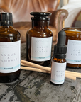 Angus & Florrie product bottles and candles on a stone surface with a blurred background